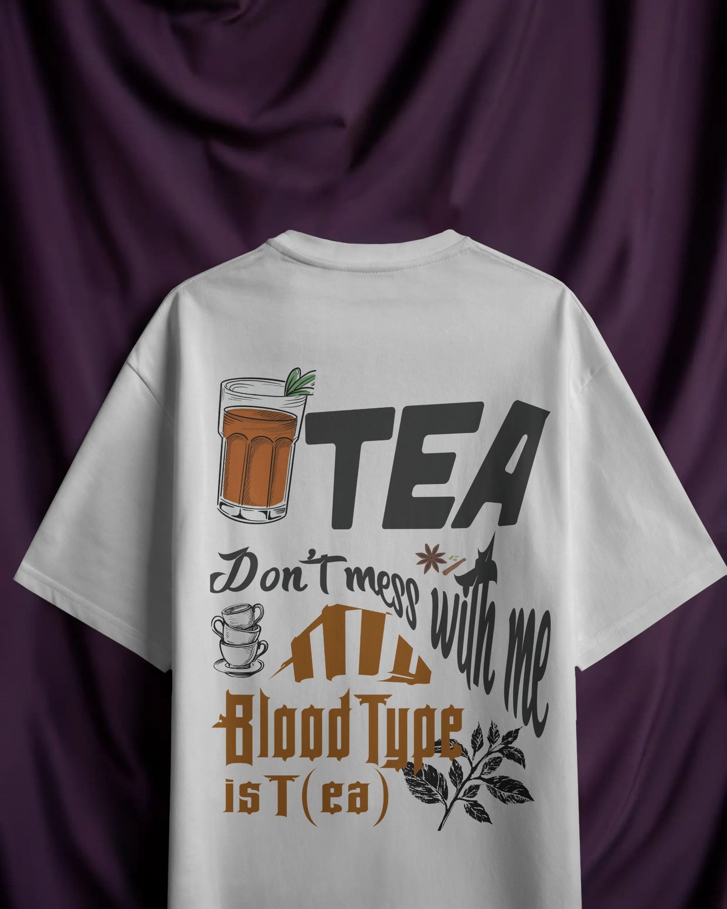 White t-shirt with tea-themed design on a purple fabric background