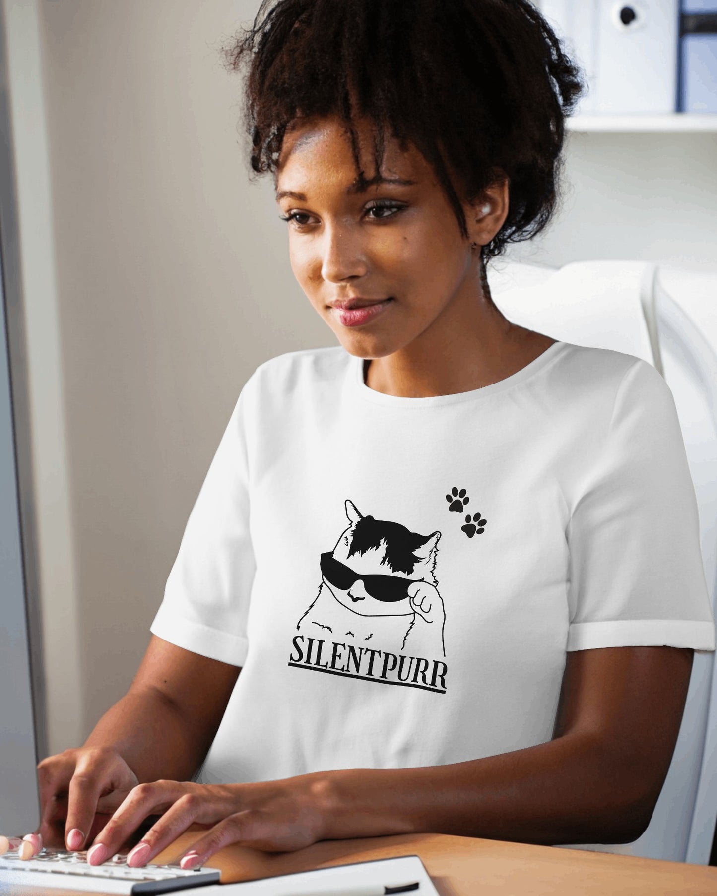 Person wearing a white t-shirt with a cat graphic and 'SILENTPURR' text, sitting at a desk.