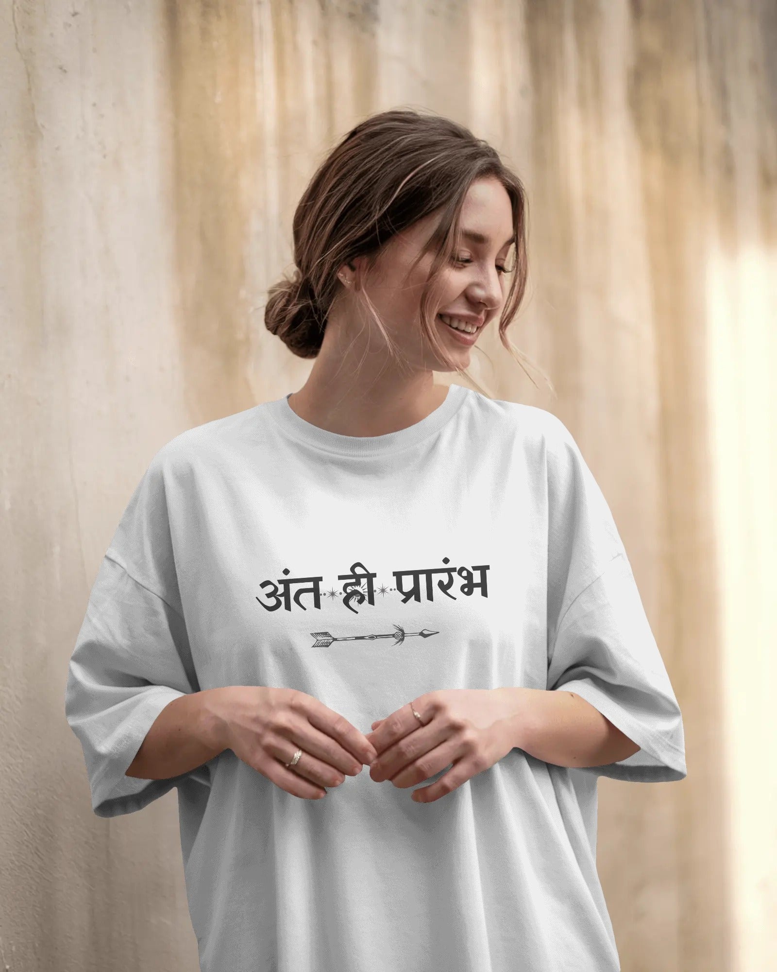 Woman wearing a white t-shirt with text against a beige curtain background
