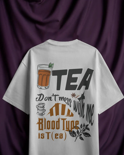 White t-shirt with tea-themed design on a purple fabric background